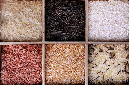 Different types of rice in box on wooden background