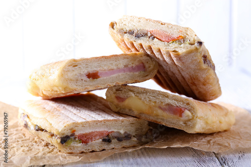 Fresh and tasty sandwiches on paper on wooden background