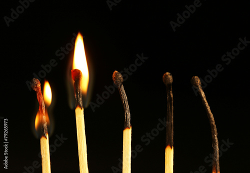 Burnt and burning matches on black background