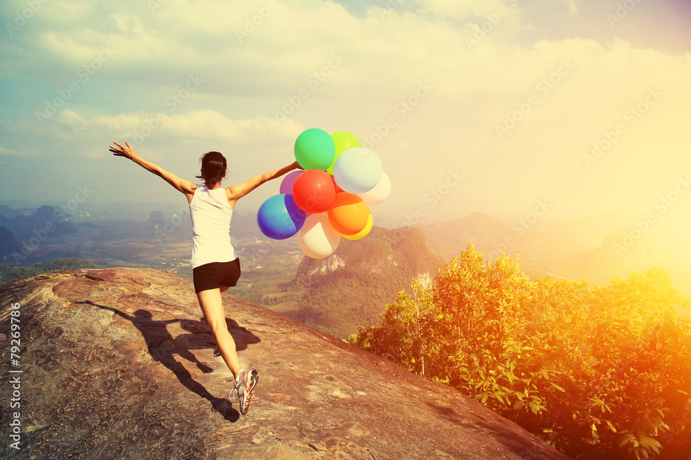 Fototapeta premium young asian woman mountain peak running with colored balloons 