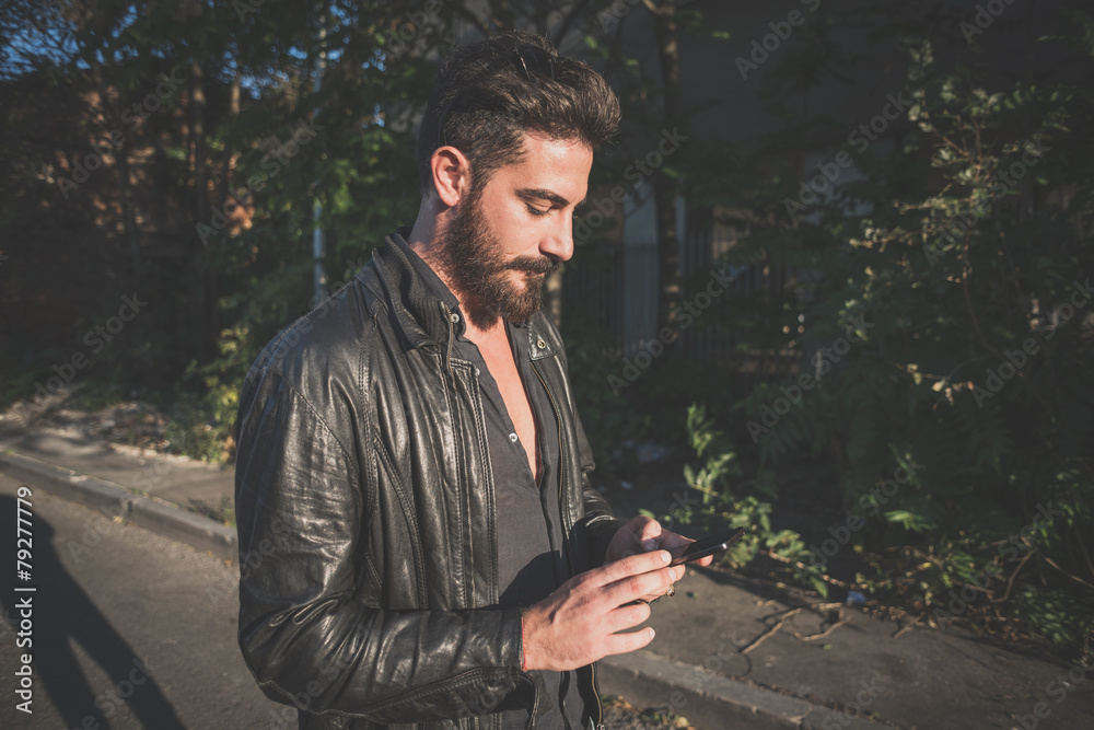 Fototapeta premium young handsome attractive bearded model man using smartphone