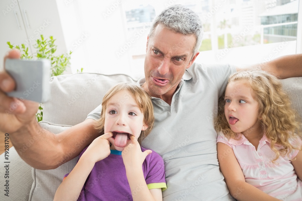 Obraz premium Father making face while taking selfie with children