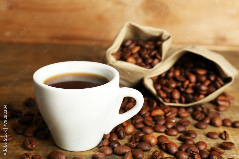 Fototapeta premium Cup of coffee with beans on rustic wooden background