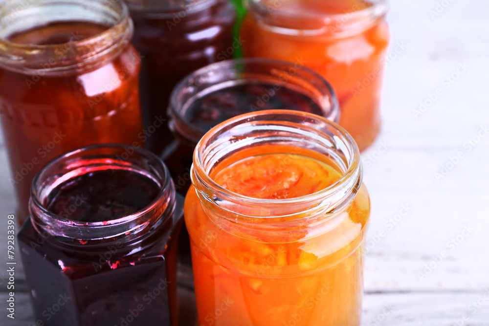 Homemade jars of fruits jam on color wooden planks background Homemade jars of fruits jam on color wooden planks background