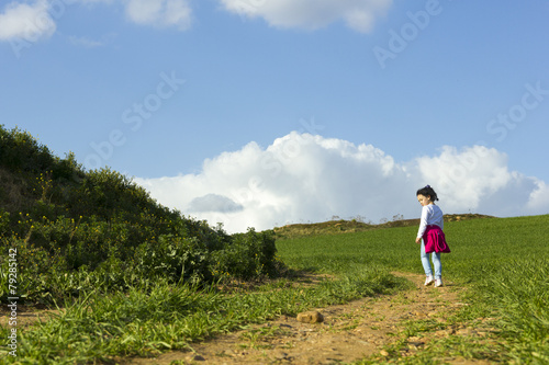 Niña corriendo y caminando feliz por el camino en el campo © Trepalio