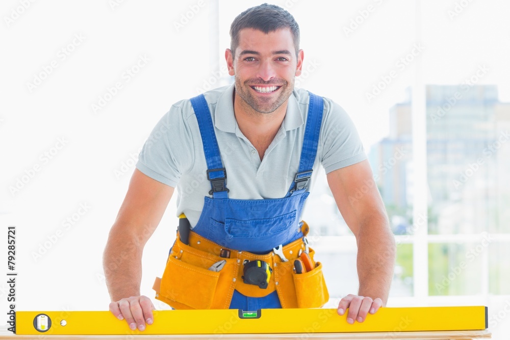 Smiling handyman using spirit level in office Smiling handyman using spirit level in office