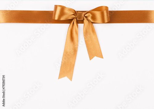 Gold satin ribbon with a bow on a white background