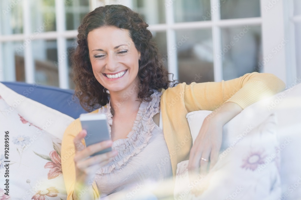 Pretty brunette relaxing on the couch with smartphone Pretty brunette relaxing on the couch with smartphone