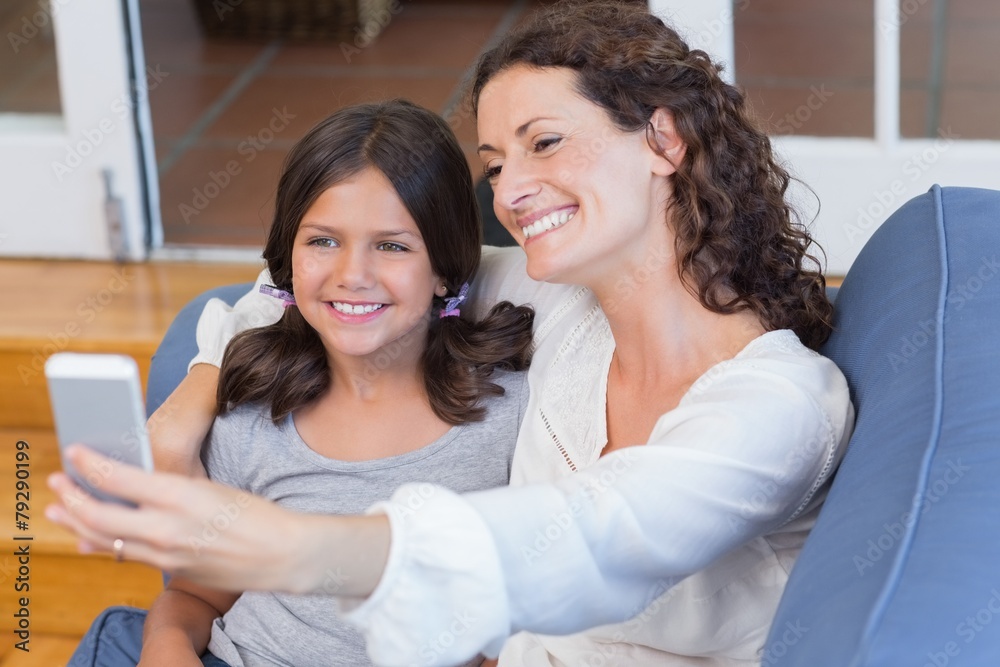Happy mother and daughter sitting on the couch and taking selfie Happy mother and daughter sitting on the couch and taking selfie