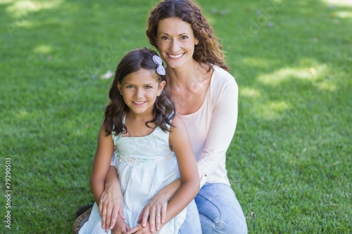 Happy mother and daughter sitting on the grass