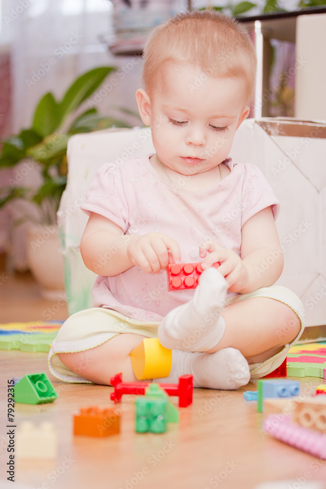 Cute little child is playing with toys while sitting on floor Cute little child is playing with toys while sitting on floor