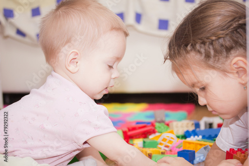 Kids play at day care. Two toddler children build tower of colorful wooden blocks.