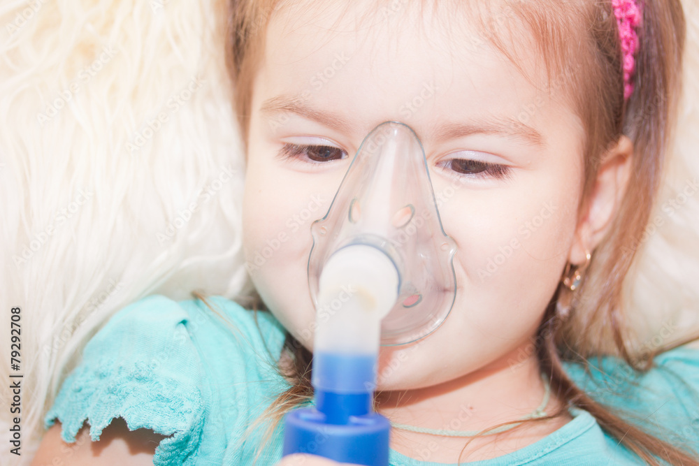 Little girl using an inhaler indoors