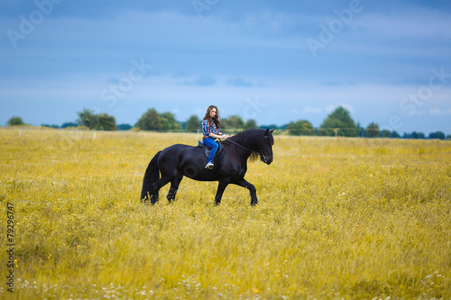 Beautiful young girl riding a horse in countryside © castenoid