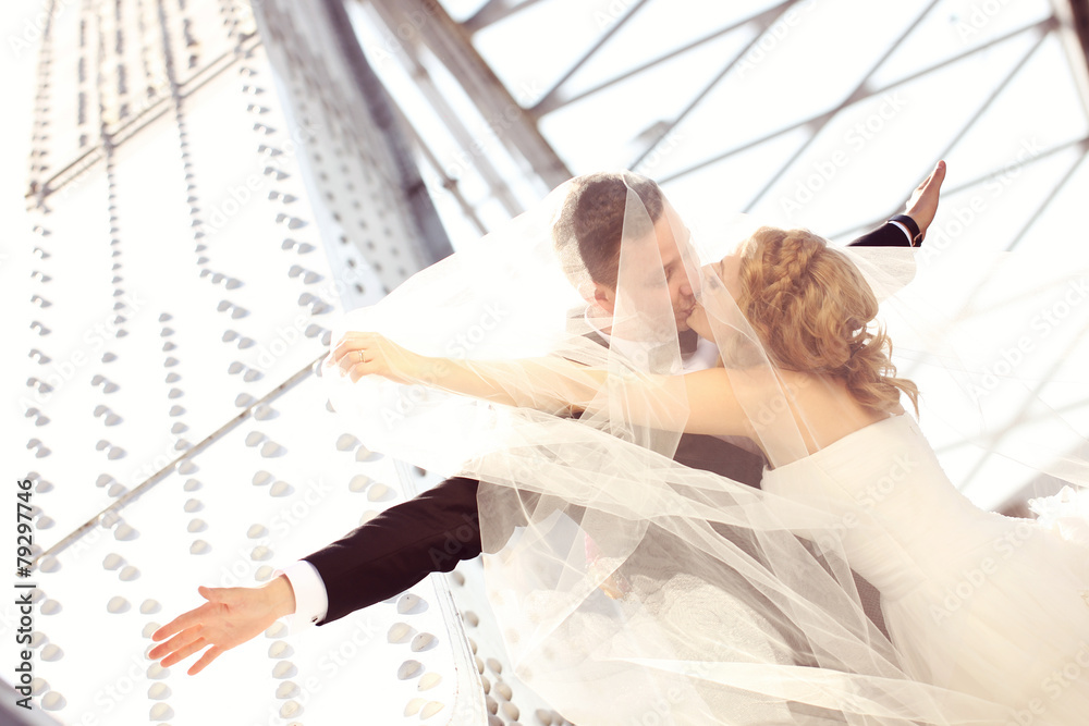 groom and bride outdoors kissing on a metalic construction groom and bride outdoors kissing on a metalic construction