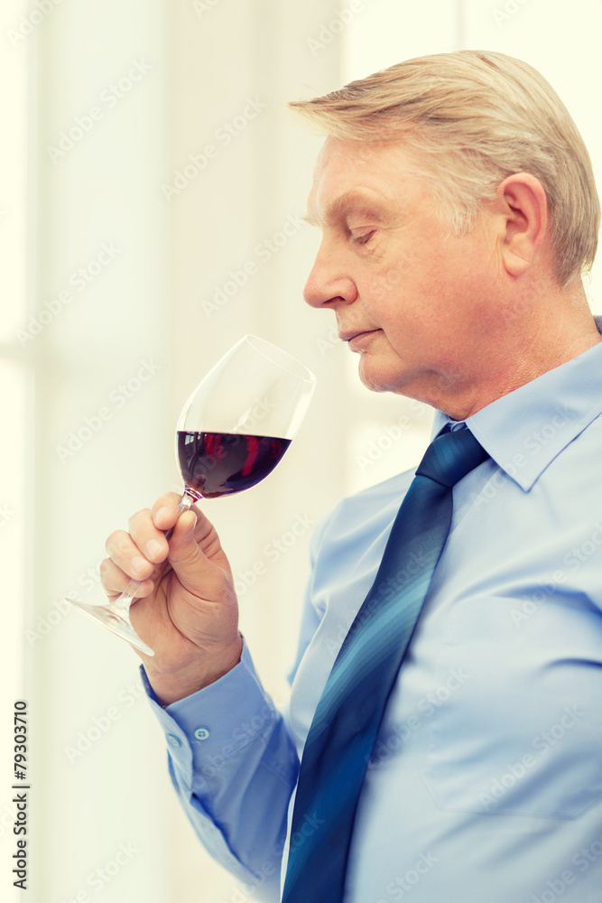 older man smelling red wine older man smelling red wine