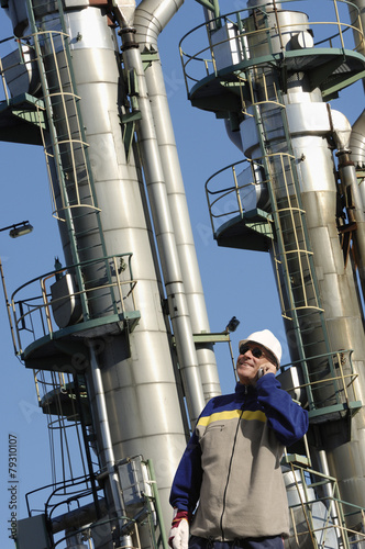 oil and gas worker with large refinery towers in background