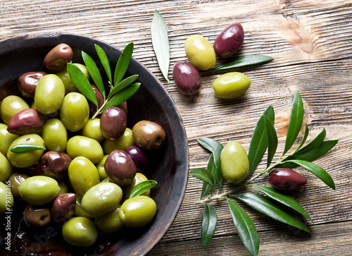 Canvastavla Wooden bowl full of olives and olive twigs besides it.