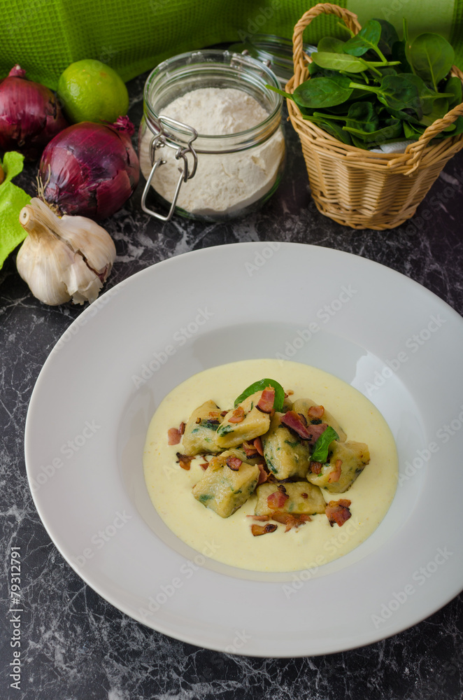 Spinach gnocchi with parmesan sauce topped with bacon Spinach gnocchi with parmesan sauce topped with bacon