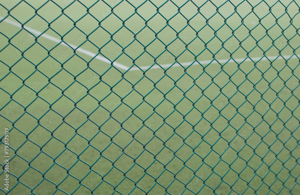 Fototapeta premium Sport field with grass behind security grid