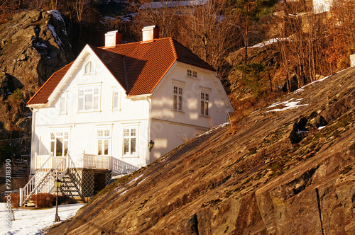 Norwegian white wooden house among rocks