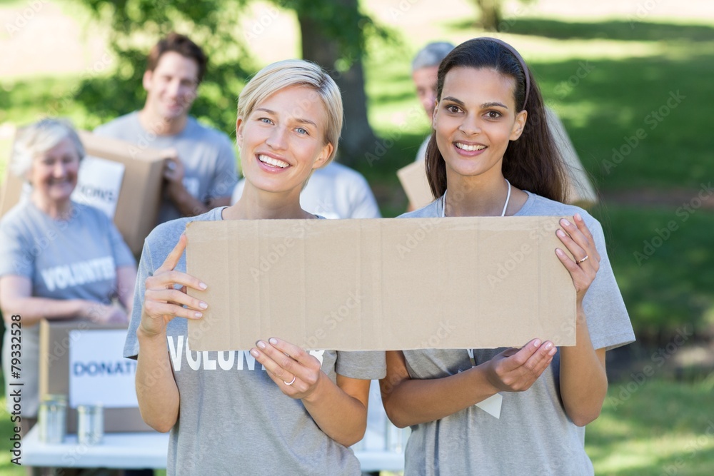 Happy volunteer friends holding blank Happy volunteer friends holding blank