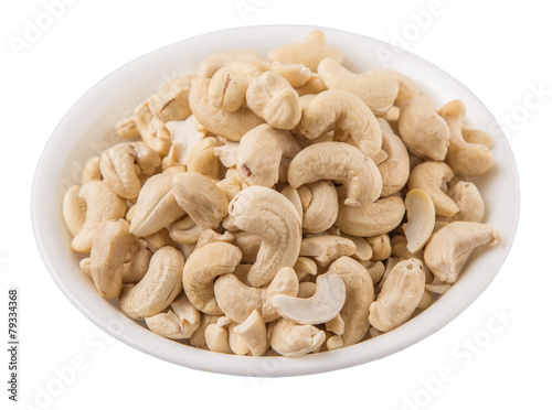 Raw cashew nuts in a white bowl over white background