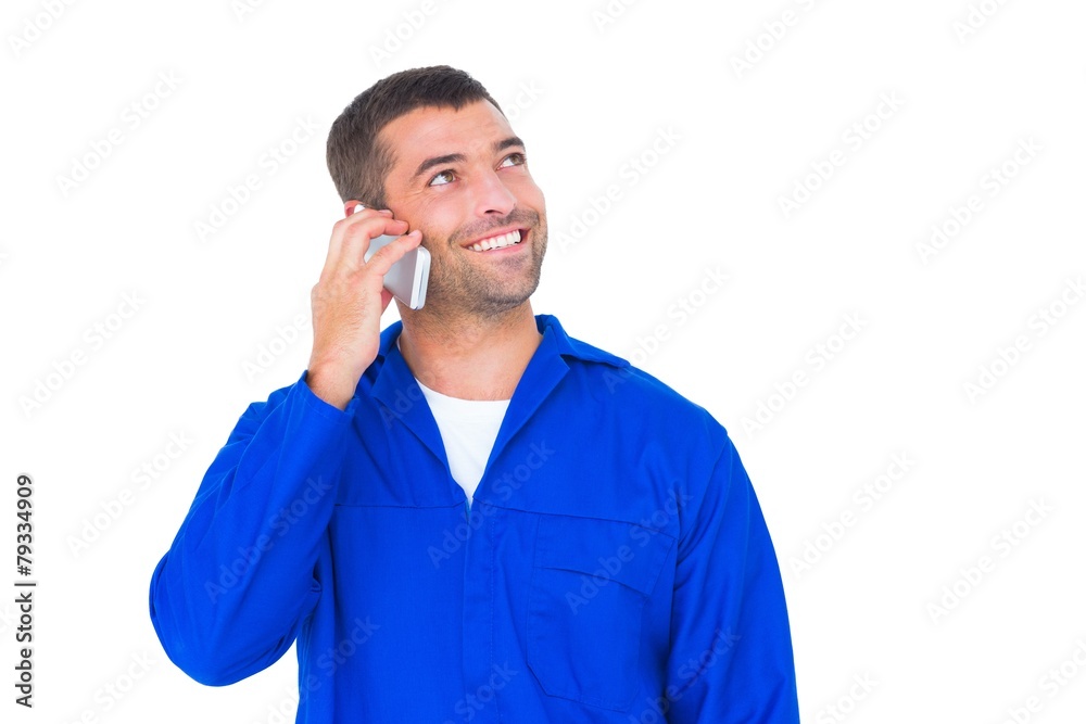 Mechanic looking up while talking on mobile phone Mechanic looking up while talking on mobile phone