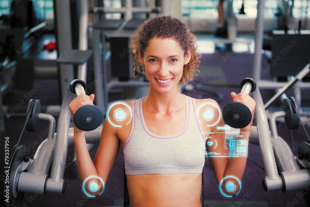 Fototapeta premium Fit smiling woman using the weights machine for her arms