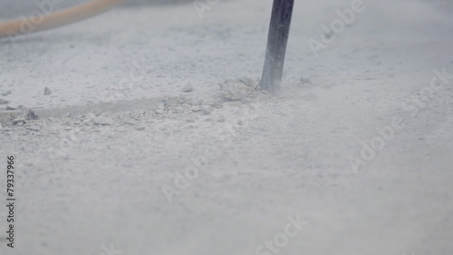 Worker drilling concrete with compressor on the street.