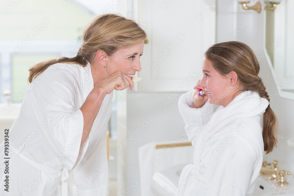Happy mother and daughter brushing teeth together Happy mother and daughter brushing teeth together