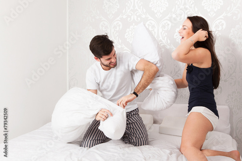 Junges Paar macht eine Kissenschlacht im Bett