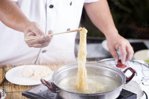 Chef holding the noodle from the pot with chopsticks