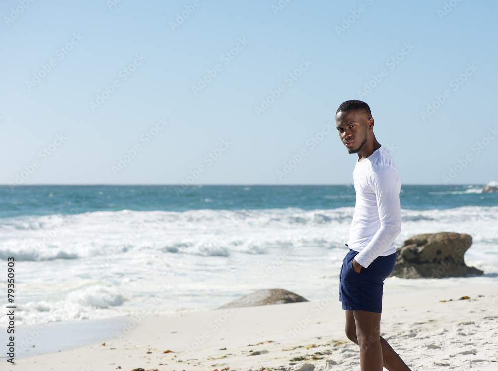 Handsome young man standing alone at the beach