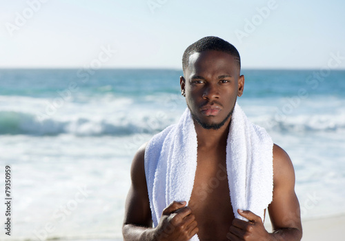 African american man standing at the beach with towel