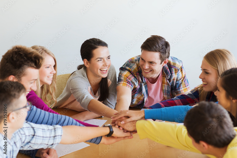 group of smiling students with hand on top group of smiling students with hand on top