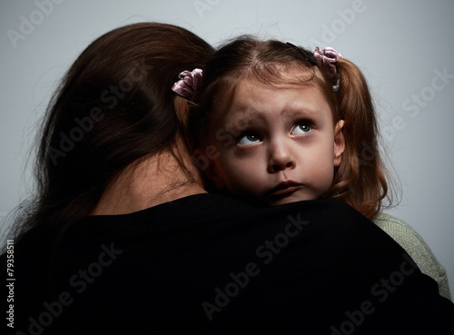 Thinking sad daughter embracing her mother and looking up