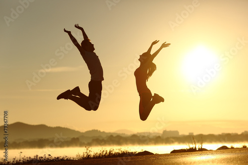 Fitness couple jumping happy at sunset photo