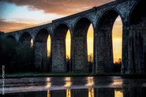 Viaduct silhouette with sunrise and clouds behind © stevie_uk