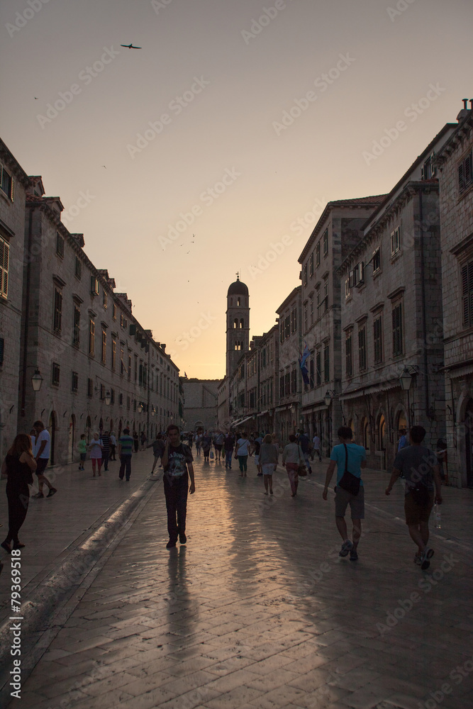 DUBROVNIK, CROATIA - MAY 26, 2014: Tourists walking on Stradun at sunset. Stradun is 300 meters long main pedestrian street in Dubrovnik.