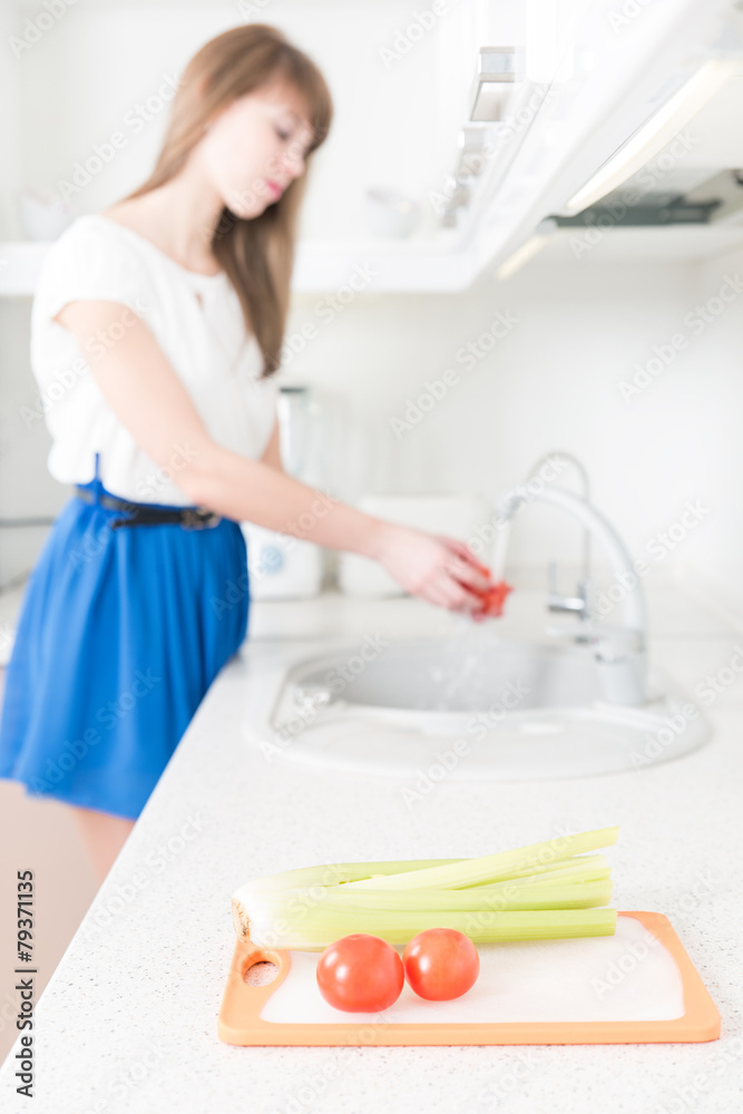 Celery and tomatoes on the foreground, young woman on the backgr Celery and tomatoes on the foreground, young woman on the backgr