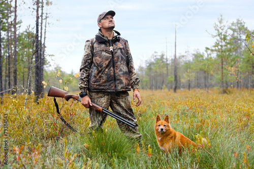 hunter with a gun and a dog on the swamp