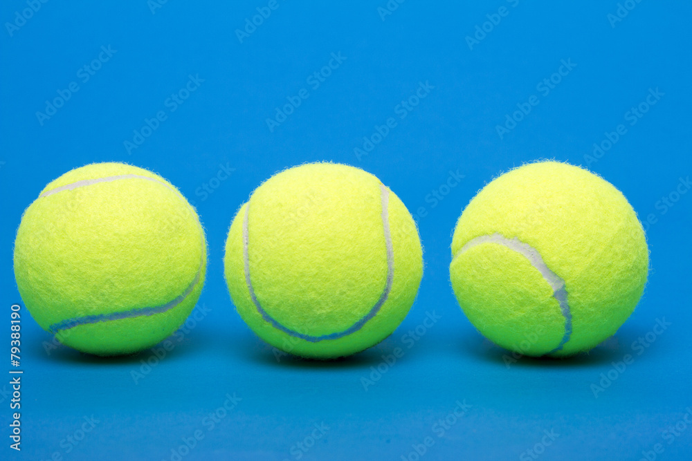 Three isolated tennis balls over a blue background.