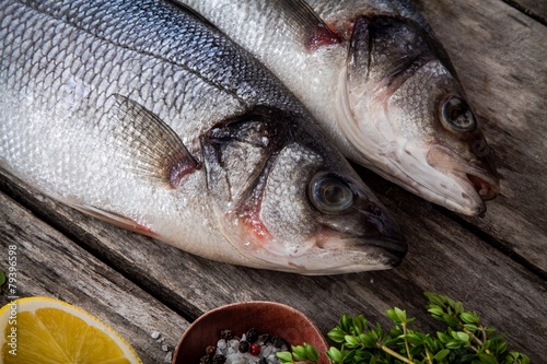 two raw fresh sea bass closeup on a rustic wooden table