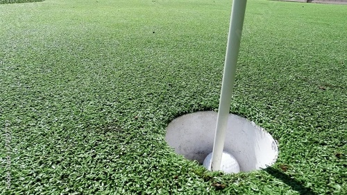 White golf ball rolling in the cup on artificial putting green