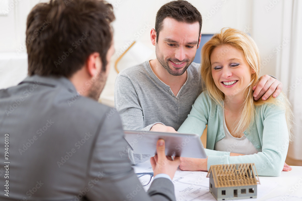 Fototapeta premium Real estate agent present project on tablet to a young couple