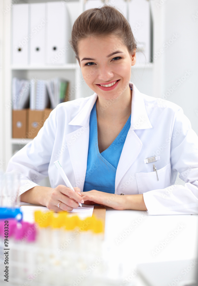 Beautiful young smiling female doctor sitting at the desk . Beautiful young smiling female doctor sitting at the desk .