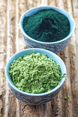 bowl of spirulina algae powder and wheat sprout powder on wooden