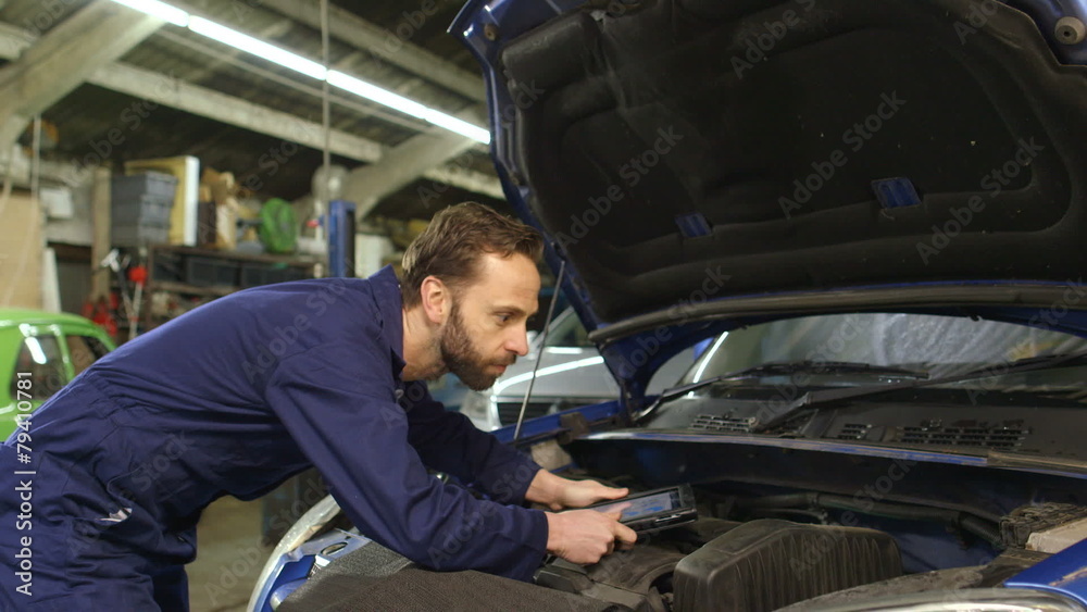 Mechanic using a digital tablet while doing routine maintenance check-up Mechanic using a digital tablet while doing routine maintenance check-up