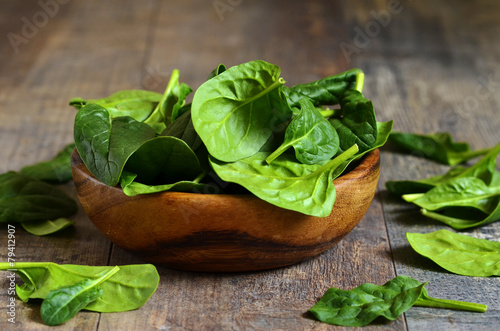 Spinach leaves in a wooden bowl.